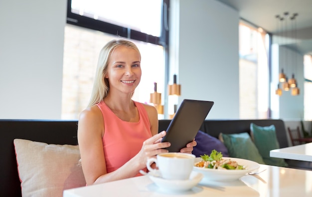 eating technology people and leisure concept happy young woman with tablet pc computer and food at restaurant