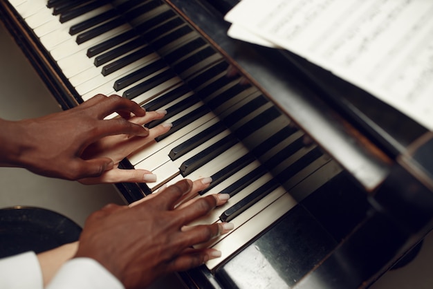 Ebony grand piano player hands on the keys, classical music. performer poses at musical instrument