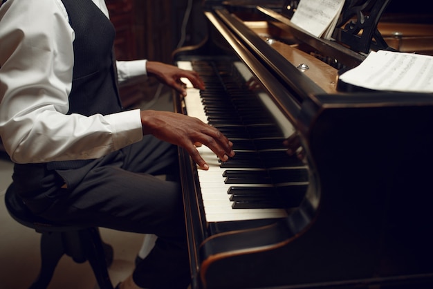 Ebony pianist, jazz performer on the stage with spotlights. musician poses at musical instrument before the concert