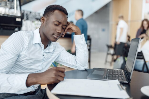 Ebony zakenman die op laptop in bureau werkt. Succesvolle zakenman op zijn werkplek, zwarte man in formele kleding