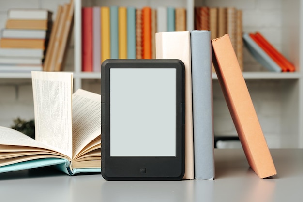 Photo ebook reader on table against book shelves