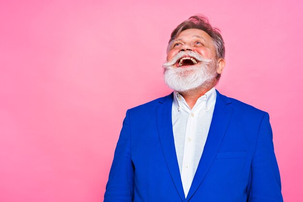 Eccentric senior man with funny expression on pink wall