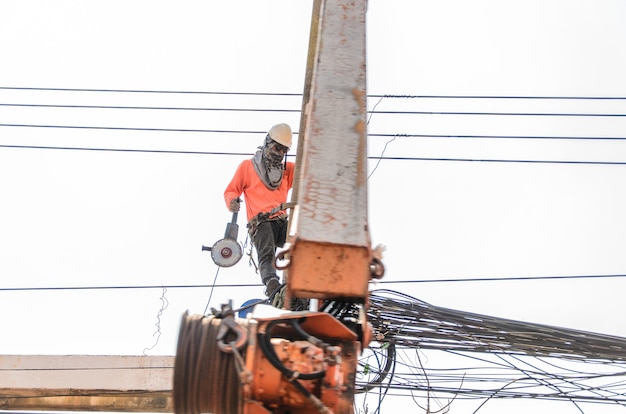 Photo echnician is repairing the power transmission line on the power post.