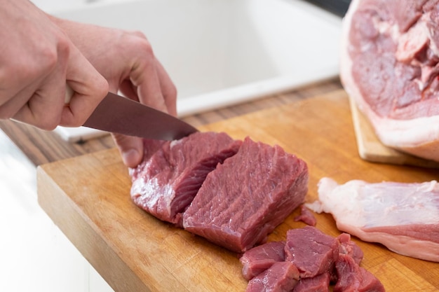 Echte mannen snijden vers rauw vlees aan boord in de witte keuken bereiden varkensvlees klaar