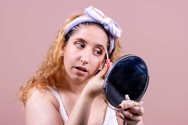 Echte vrouw jong meisje dat make-up aanbrengt met een spiegel in haar hand