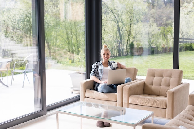 Echte vrouw met behulp van laptop thuis koffie drinken genieten van ontspannen