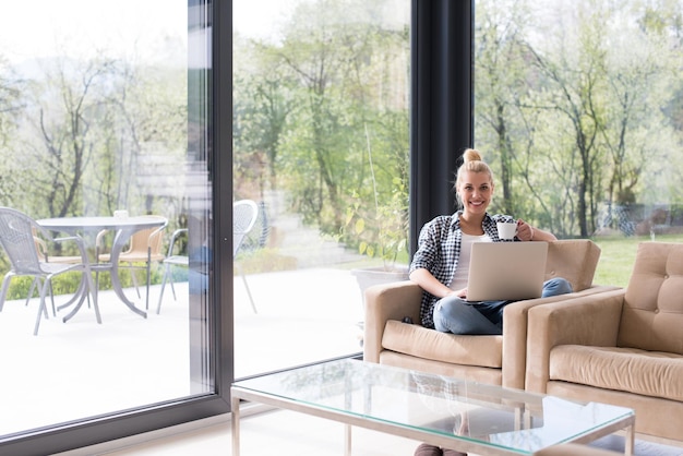 Echte vrouw met behulp van laptop thuis koffie drinken genieten van ontspannen