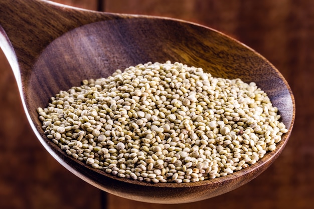 Echte witte quinoa in een naturel houten lepel met kleikom. Bovenaanzicht