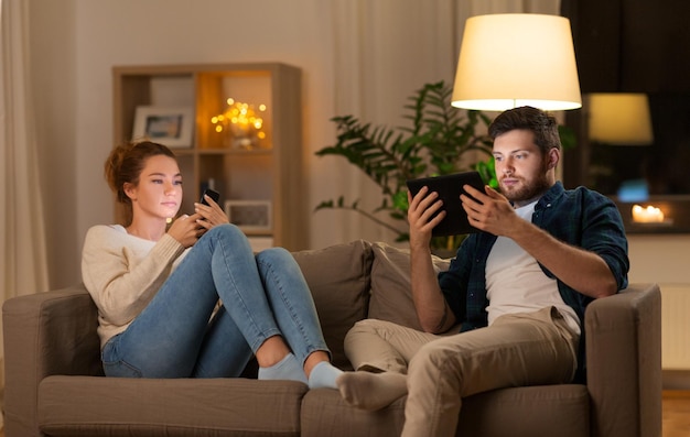 echtpaar met een tabletcomputer en een smartphone thuis