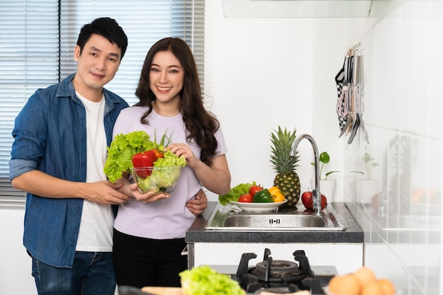 Echtpaar met het voorbereiden van groenten om samen in de keuken thuis te koken man knuffelt vrouw