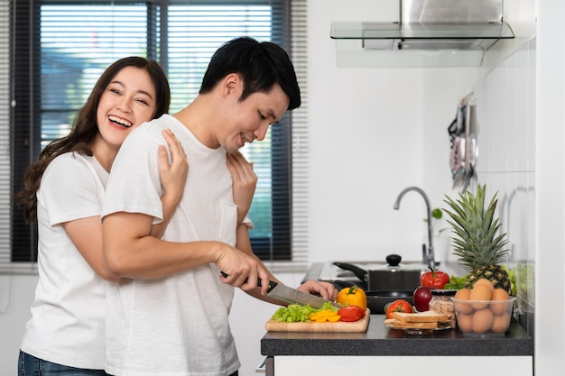 Echtpaar met het voorbereiden van groenten om samen in de keuken thuis te koken vrouw knuffelt man