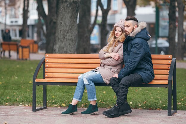 echtpaar met jas in park zit op een bankje