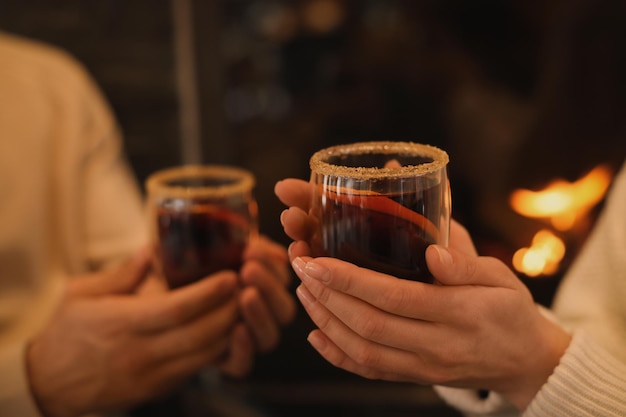 Echtpaar met lekkere glühwein in de buurt van open haard binnenshuis close-up