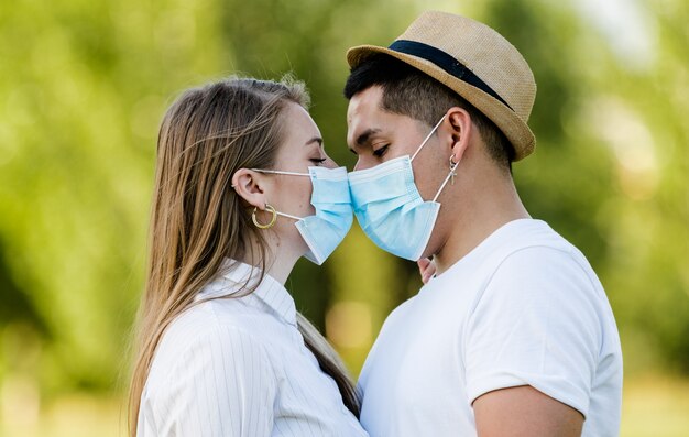 Echtpaar met masker kussen in park