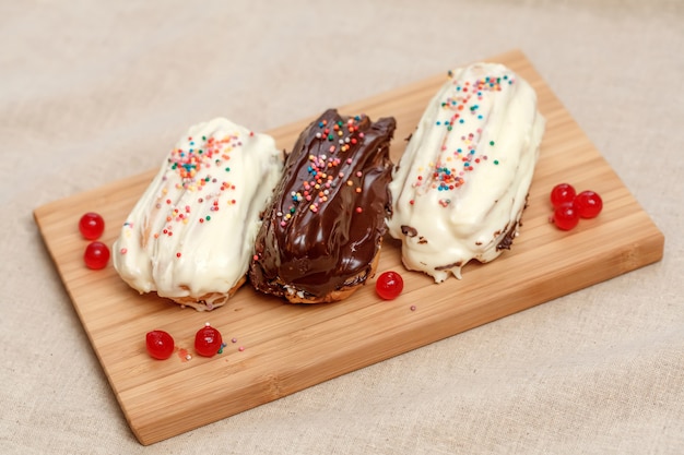 Eclair cakes with white and brown cream on wooden board