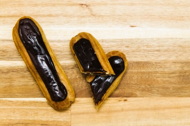 Eclair crispy creamy cake with dark chocolate isolated on wooden surface