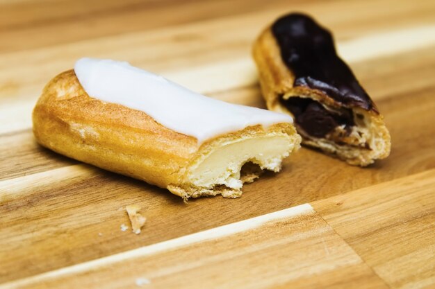 Eclair torta cremosa croccante con cioccolato bianco e fondente isolato su superficie di legno