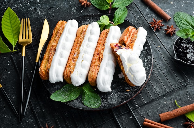 Eclair met room Romig dessert op een zwarte stenen plaat Bovenaanzicht Rustieke stijl