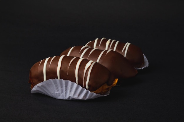 Eclair with chocolate filling on black surface.