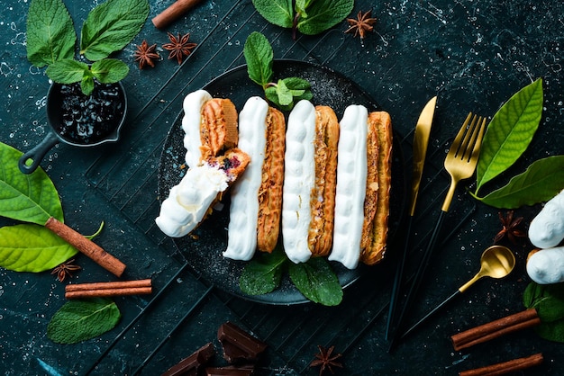 Eclair with cream Creamy dessert on a black stone plate Top view Rustic style