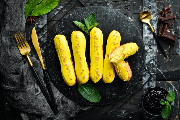 Eclair with mango cream Mango dessert on a black stone plate Top view Rustic style