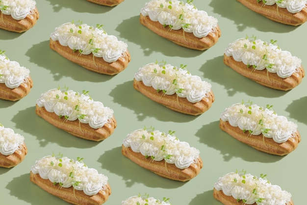 Eclair with salty cream and sprouts on a green background with a shadow from a palm tree top view space for text modern style