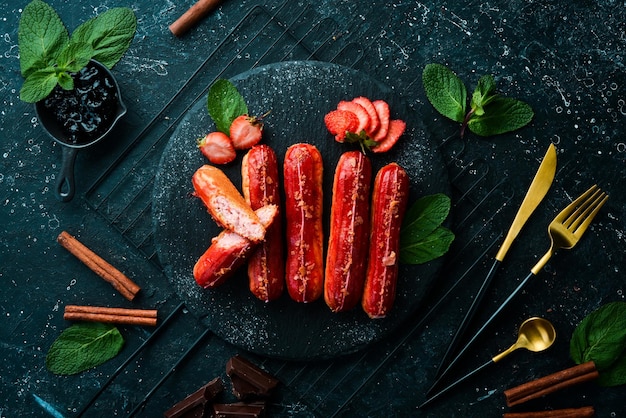 Eclair with strawberry cream Strawberry dessert on a black stone plate Top view Rustic style