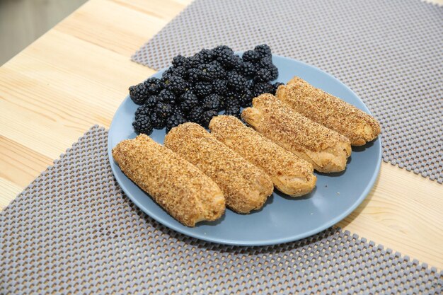 eclairs and blackberries on a blue plate