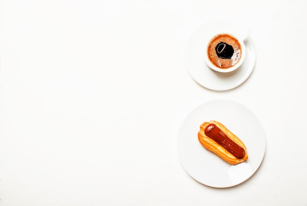 Eclairs cake en espresso koffie met schuim witte achtergrond bovenaanzicht