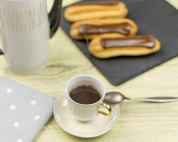 Eclairs en koffie op een houten ondergrond