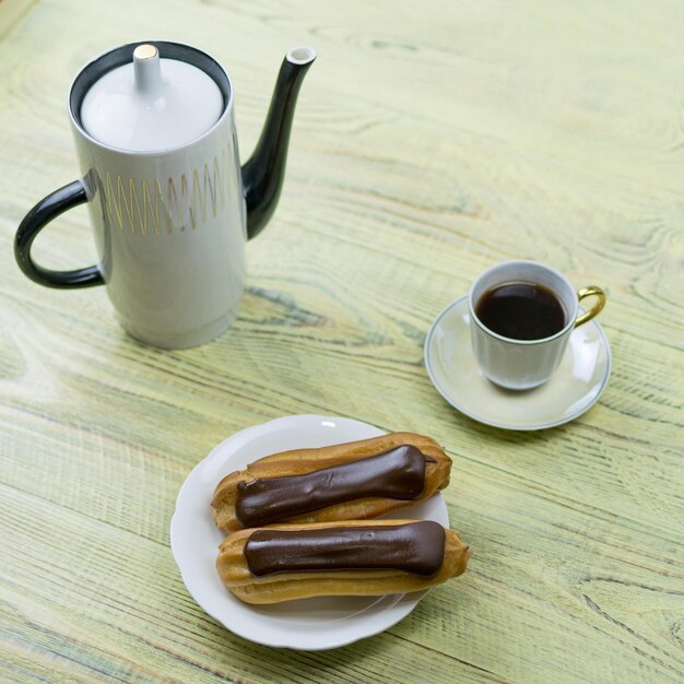 Eclairs en koffie op een houten ondergrond