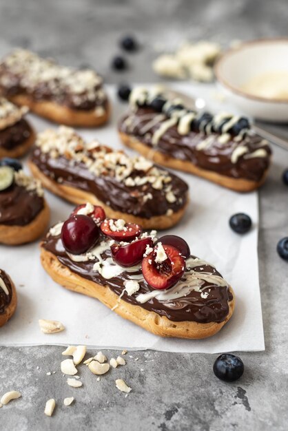 Eclairs met chocolade topping noten en bessen op een betonnen ondergrond