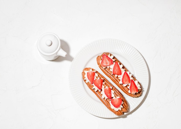 Eclairs met room en aardbeien op een wit bord