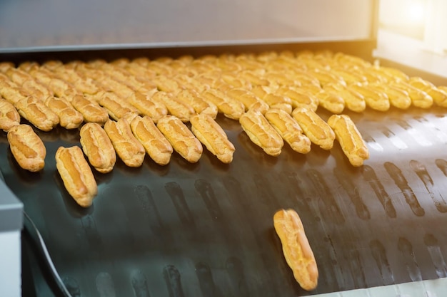 Eclairs op grote transportband Veel gebakken gebak Populair dessert geproduceerd in fabriek Zaken die een goed inkomen opleveren