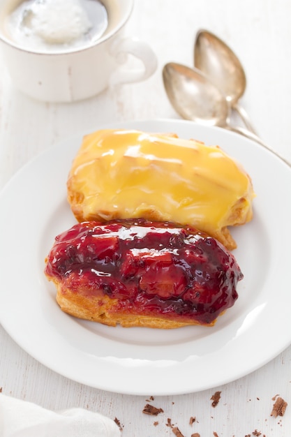 Eclairs on white dish on wooden surface