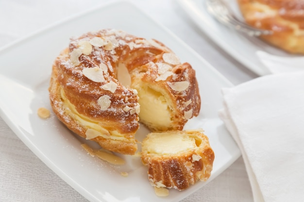 Eclairs with vanilla cream and almonds.  Profiterole on a white plate