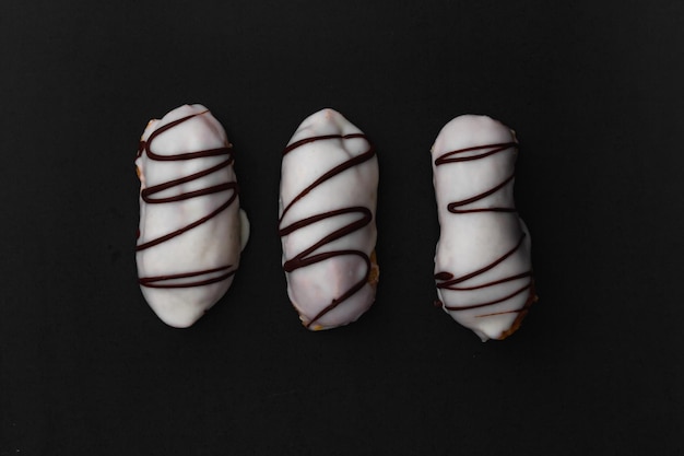 Eclairs with white chocolate filling on a black surface.