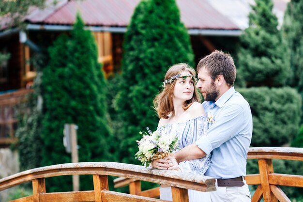 屋外の折衷的な結婚式のカップル。新郎新婦が橋の上に立つ