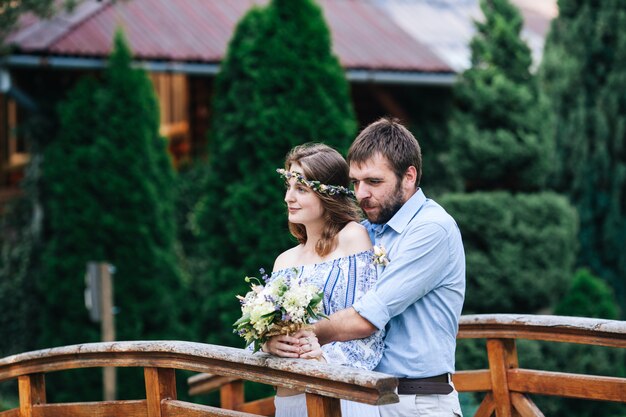 Eclectic wedding couple outdoor. Bride and groom stand on the bridge