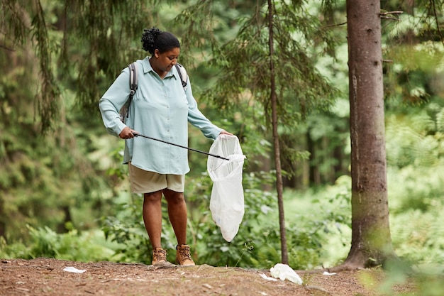 Eco-activiste zwarte vrouw die het spoor van plastic flessen oppakt