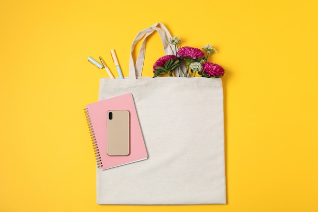 Eco bag, phone, allium and chrysanthemum on color background