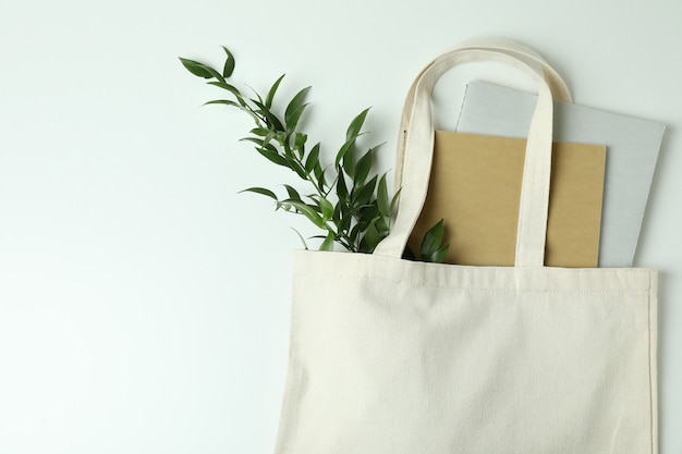 Photo eco bag with copybooks and twig on white background