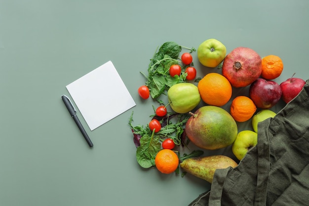 Eco bag with products on color background and a pen with a sheet of paper