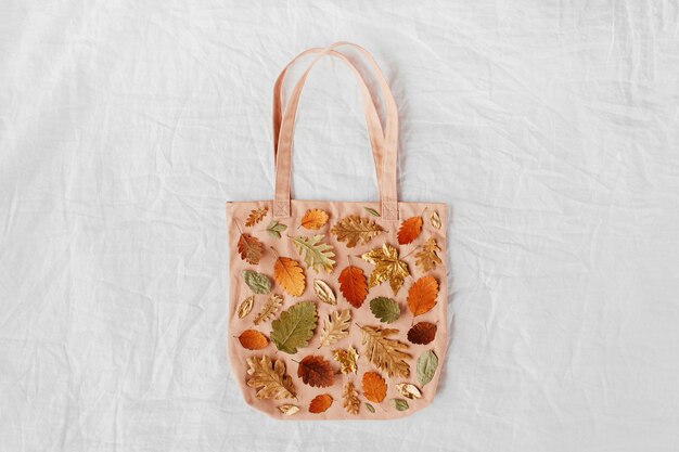 Eco bags with pattern made of autumn leaves. fall composition.\
flat lay, top view, copy space