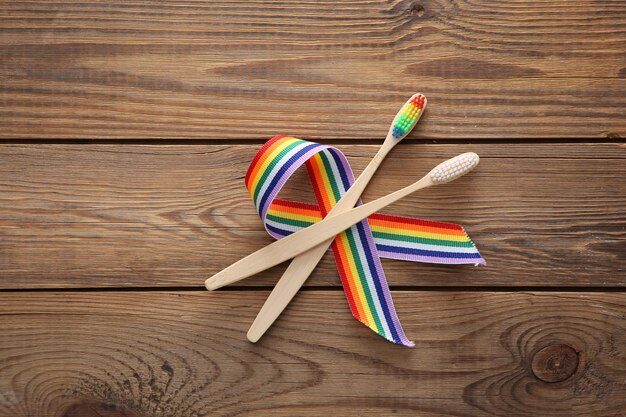 Eco bamboe tandenborstels met LGBT regenboog lint trots tape symbool op houten achtergrond bovenaanzicht