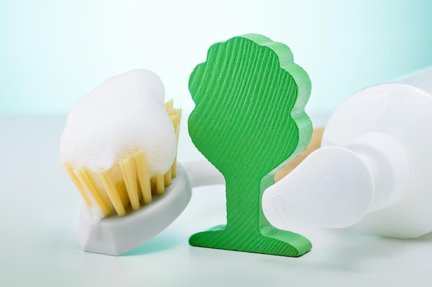 Eco brush with foam bottle and model of green wooden tree on white background Eco cleaning products