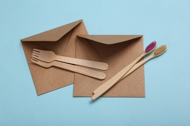 Eco concept Craft envelope wooden toothbrushes and forks on blue background