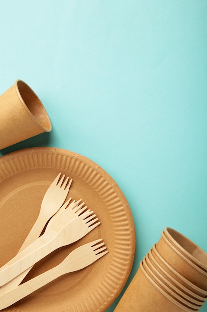 Eco craft paper tableware. paper cups, dishes, bag, fast food containers and wooden cutlery on blue background. zero waste. recycling concept. vertical photo