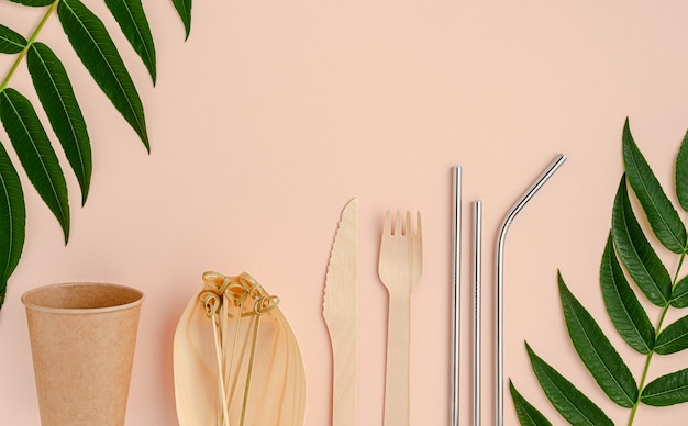 Eco cutlery and metal drinking straws on pink background