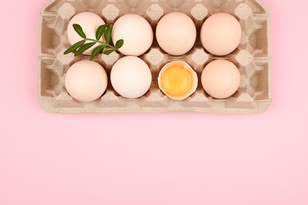 Photo eco eggs on a pink background. a tray of eggs on a white and pink background. eco tray with testicles. minimalistic trend, top view. egg tray. easter concept.